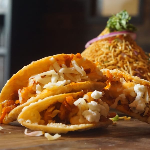 Inchin's Bamboo Garden's fusion tacos with shredded cheese and a side of noodles.