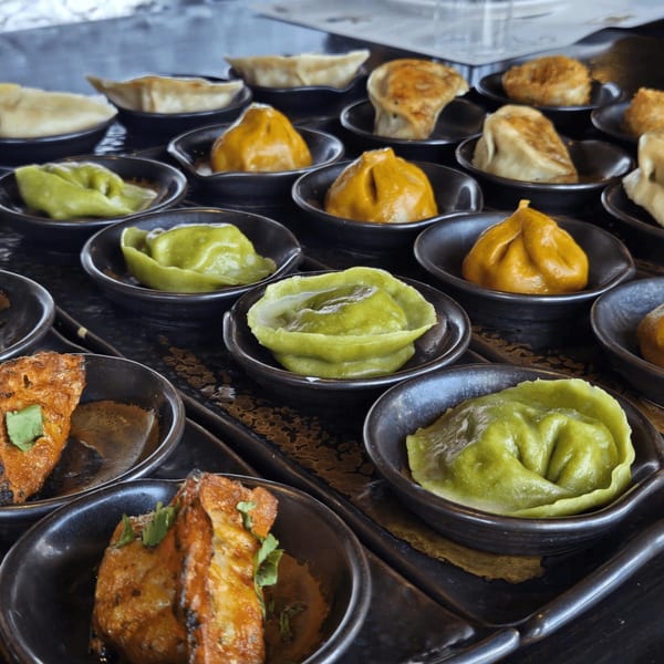Assortment of Inchin's Bamboo Garden's colorful dumplings and appetizers in small black dishes.