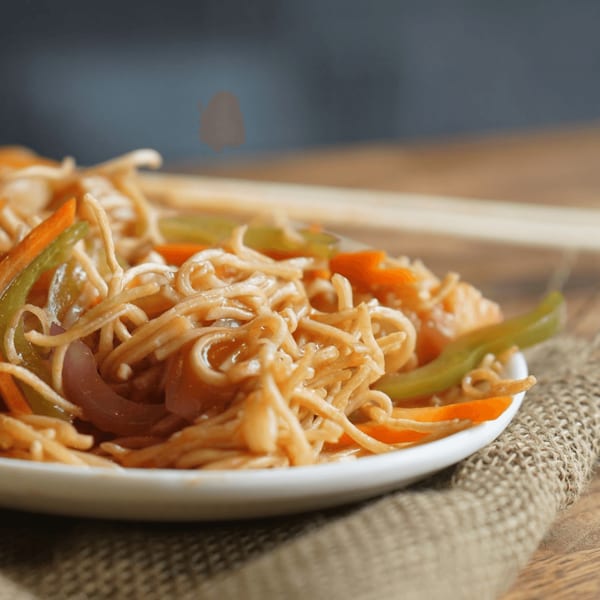 Close-up of Inchin's Bamboo Garden's noodles with colorful vegetables on a white plate.