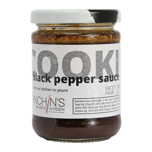 A jar of Inchin's Bamboo Garden black pepper sauce with a white and black lid.