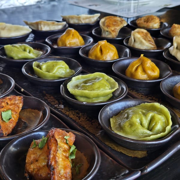 A variety of colorful Inchin's Bamboo Garden dumplings and appetizers in small black dishes.