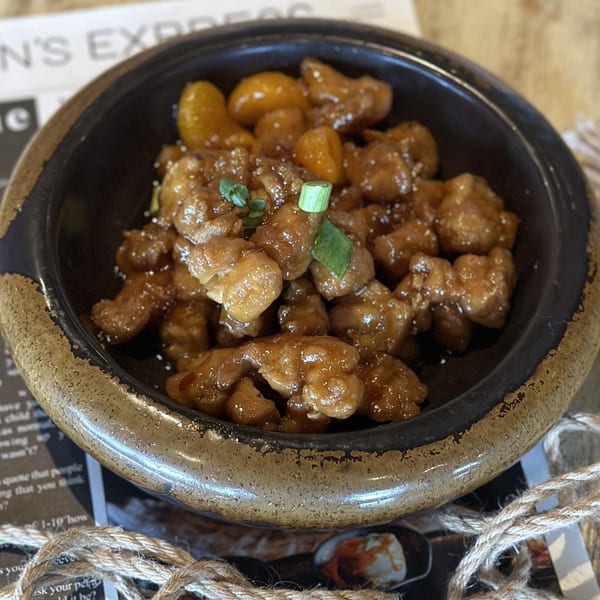 Inchin's Bamboo Garden's Asian-fusion dish with glazed chicken and kumquats, garnished with green onions.
