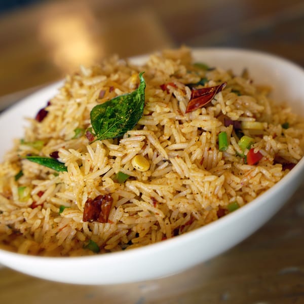 Close-up of Inchin's Bamboo Garden's fried rice with green onions, red peppers, and a curry leaf.