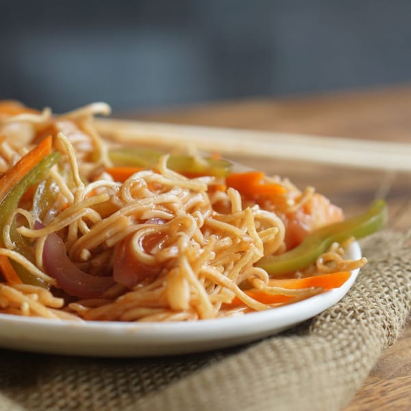 Close-up of Inchin's Bamboo Garden's Asian-fusion noodles with colorful vegetables on a white plate.